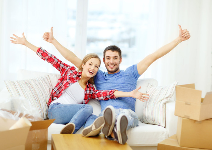 smiling couple relaxing on sofa in new home